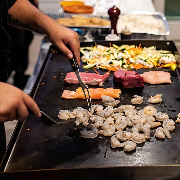Chef cooking shrimp, salmon, beef, and vegetables on a hibachi grill at Hibachi Bus Stop.