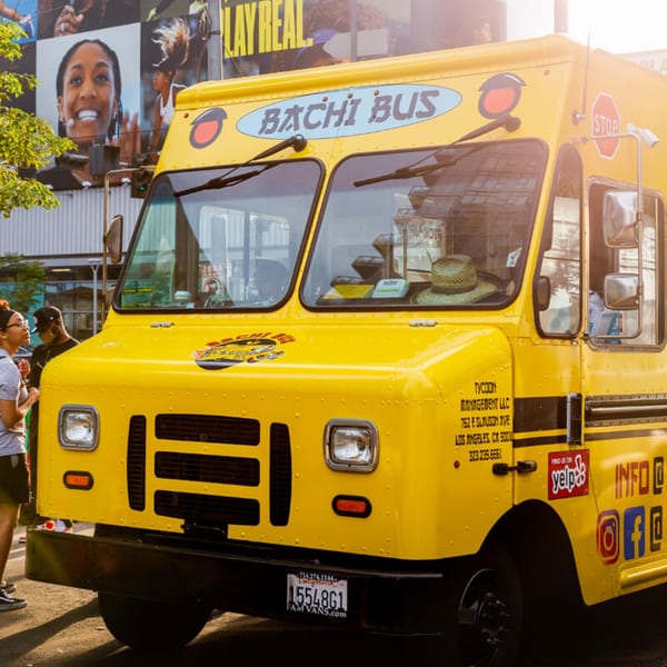 The bright yellow Hibachi Bus Stop food truck parked on a sunny street.