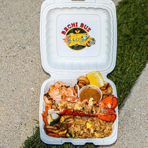 Hibachi Bus Stop takeout container with salmon, lobster, shrimp, fried rice, and vegetables.