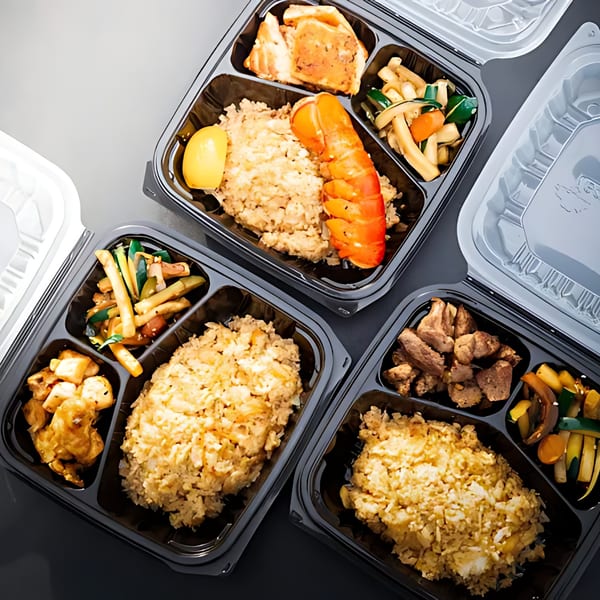 Three Hibachi Bus Stop takeout containers filled with hibachi rice, lobster, chicken, and vegetables.