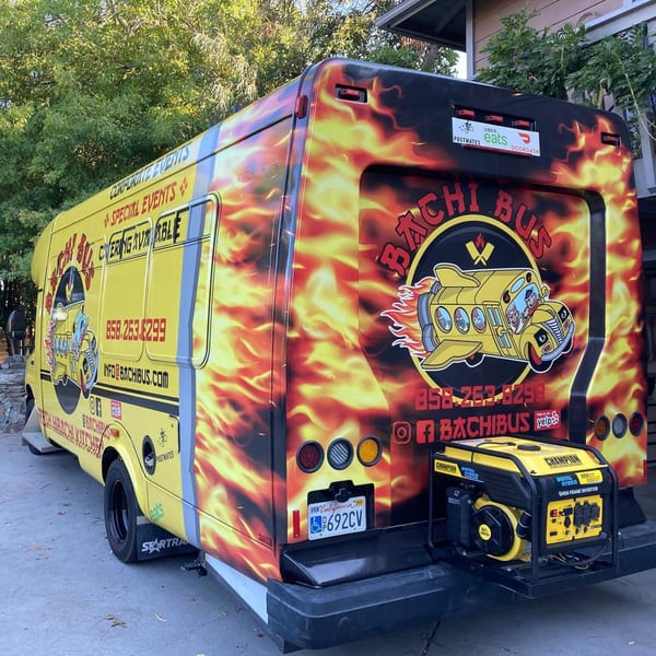 The Hibachi Bus Stop food truck, a yellow bus with flame decals, parked outdoors.