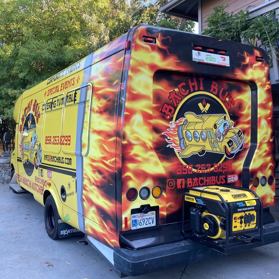 The Hibachi Bus Stop food truck, a yellow bus with flame decals, parked outdoors.