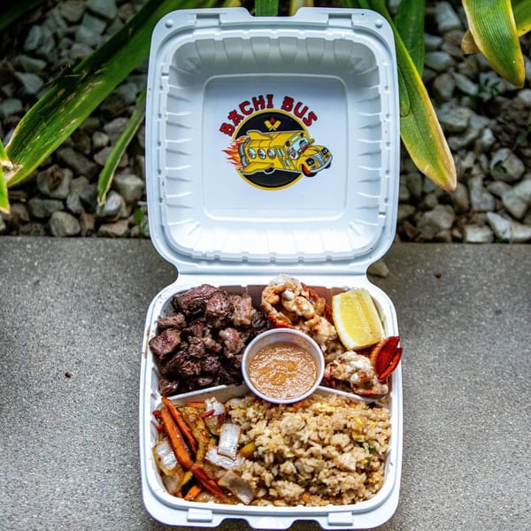 Hibachi Bus Stop takeout container with steak, lobster, fried rice, vegetables, and sauce.
