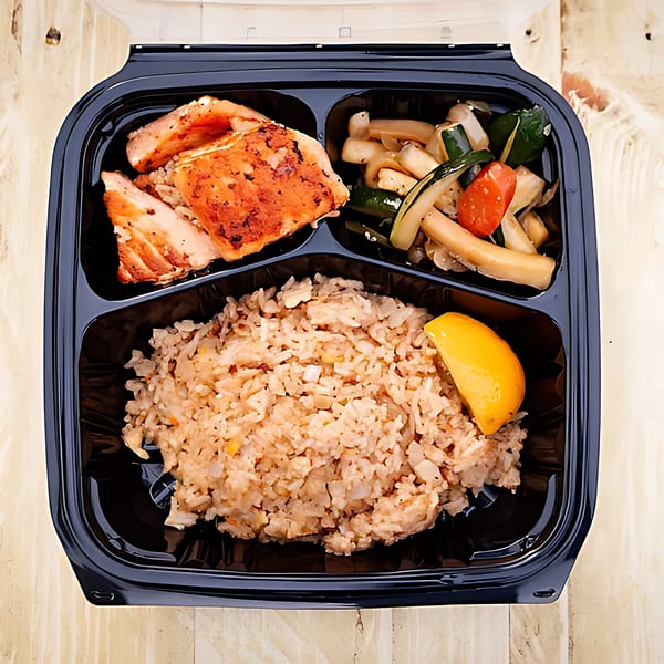 Hibachi Bus Stop's hibachi chicken, fried rice, and mixed vegetables in a black takeout container.