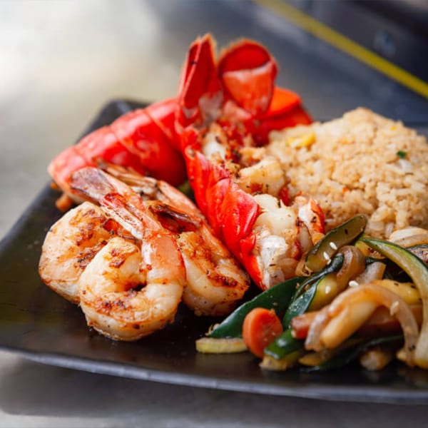 Hibachi Bus Stop's lobster, shrimp, fried rice, and mixed vegetables on a black plate.