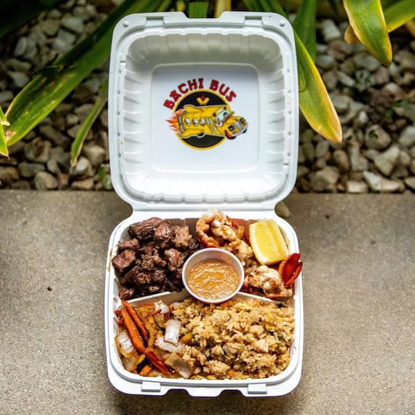 Hibachi Bus Stop takeout box with steak, lobster, fried rice, vegetables, sauce, and lemon.